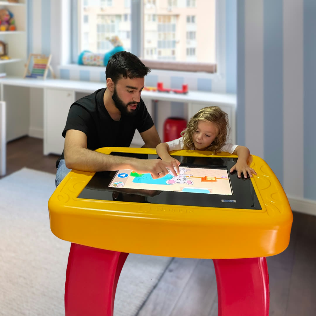 Criança utilizando a Mesinha Digital vermelha e azul